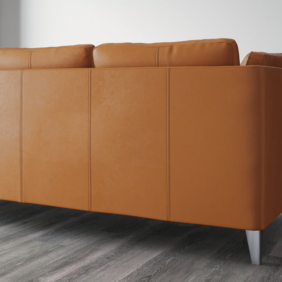 Brown leather sofa on a wooden floor with a white wall background