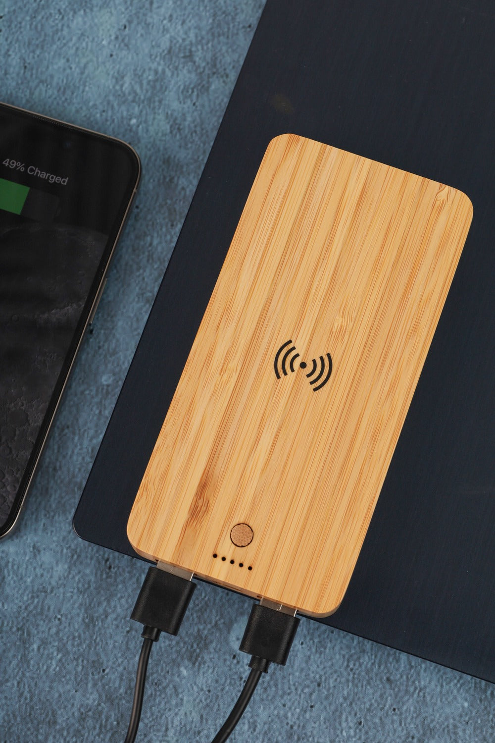 Wooden wireless charging pad with phone showing battery charge on a dark surface