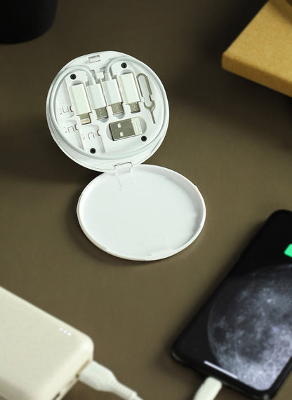 White travel-sized Mini Travel Cable Kit  with open lid on a brown surface