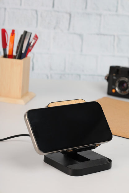 Black smartphone stand with a phone on a white surface, with a light gray brick wall in the background.