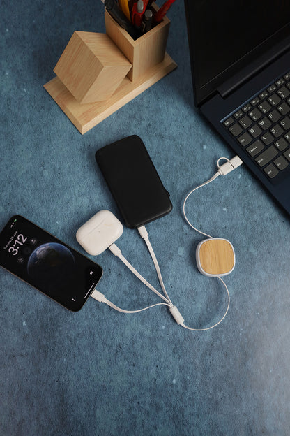 Smartphone, external hard drive, and USB device on a blue surface with a laptop in the background.