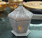 Decorative metal lantern on a reflective surface with a blurred background