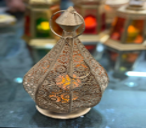 Decorative bottle with intricate designs and a lid on a dark background