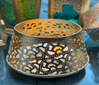 Decorative metal bowl with cut-out patterns on a dark surface