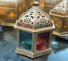 Decorative lantern with stained glass interior on a reflective surface