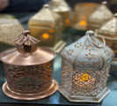 Decorative metal containers with intricate designs on a reflective surface