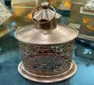 Decorative oil lamp with intricate design on a reflective surface