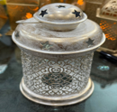 Decorative metal lantern with intricate designs on a reflective surface