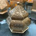 Decorative metal lantern with intricate patterns on a dark background