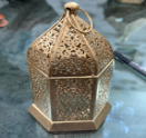 Decorative metal lantern with intricate design on a reflective surface