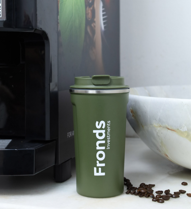 Green tumbler with 'Fronds Investments' branding next to a coffee machine and coffee beans.