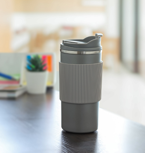 Gray travel mug on a desk with a blurred office background