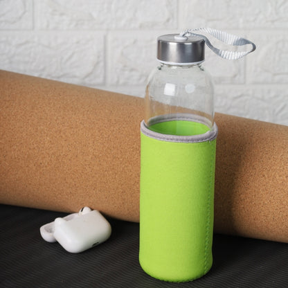 Clear glass bottle with green sleeve and silver cap on a cork mat.