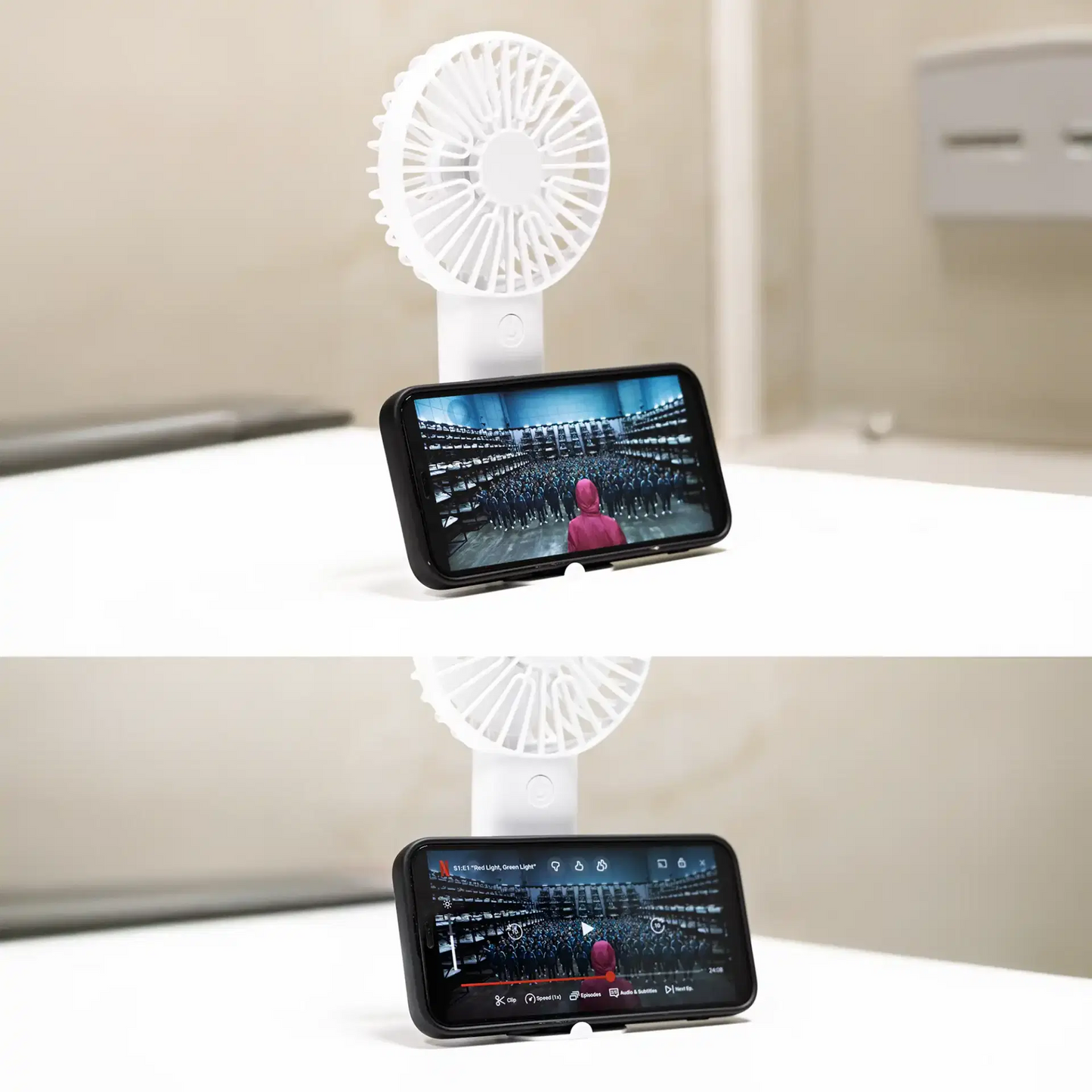 Handheld fan with smartphone holder displaying a phone screen on a white surface.