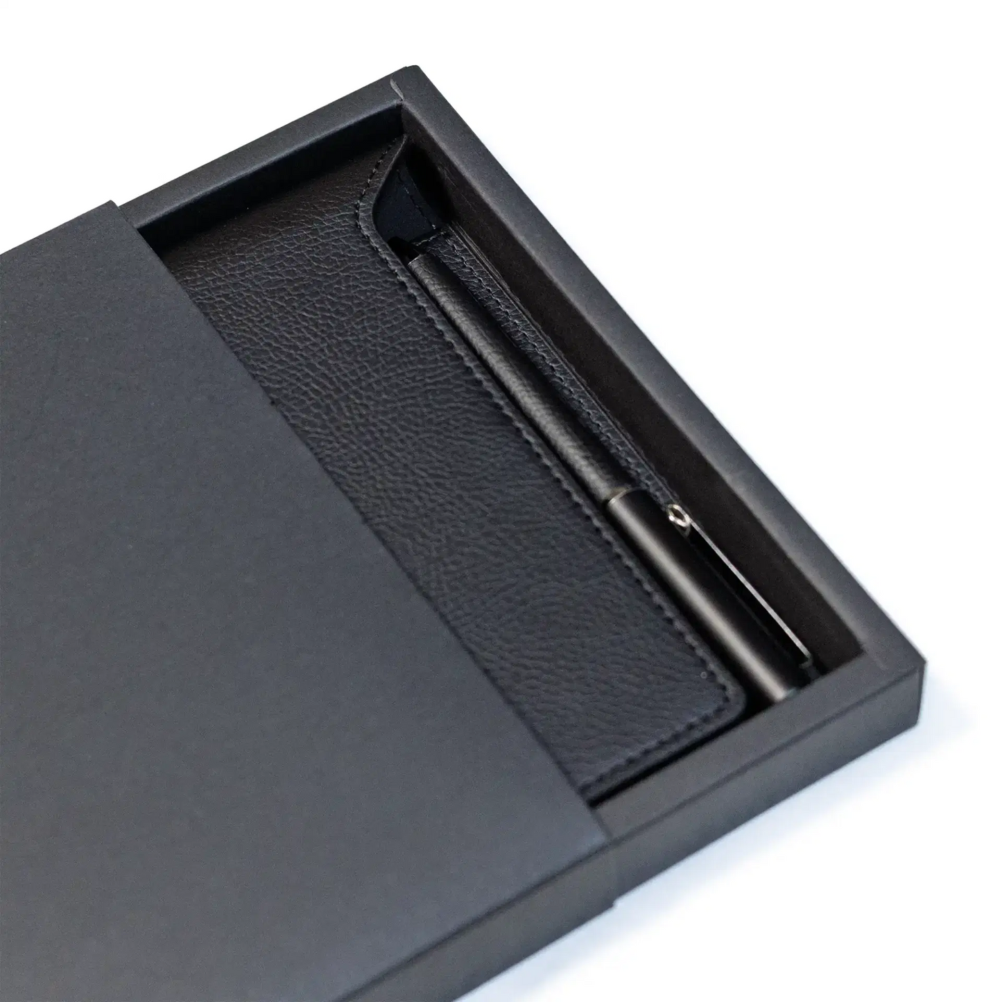 Black leather notebook and pen set in a box on a white background